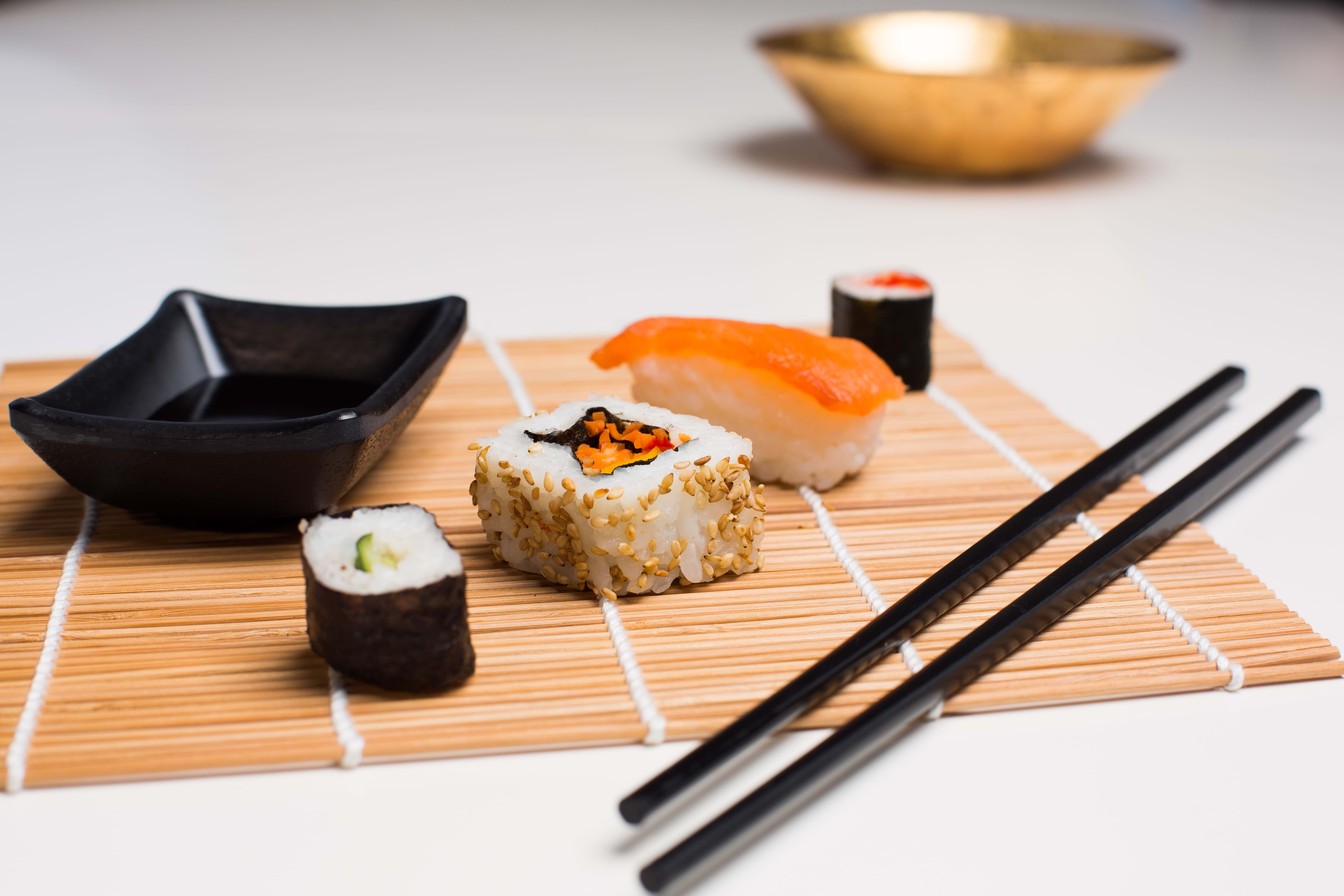 Photo of some pieces of sushi with chopsticks and small sauce bowl alongside it