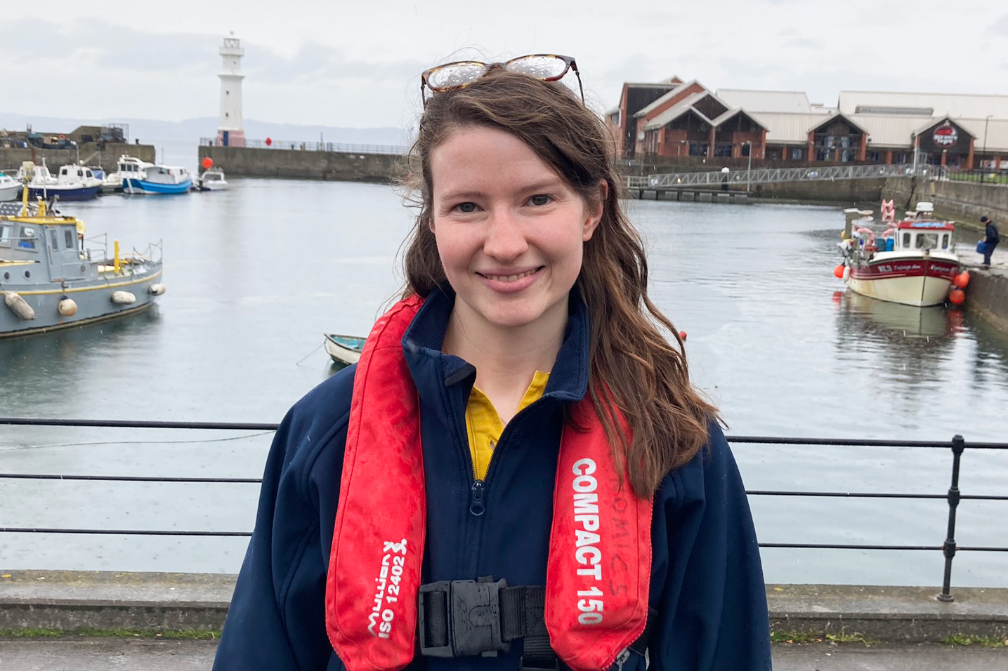 Field Researcher Felicity at a harbour in front of fishing boats.