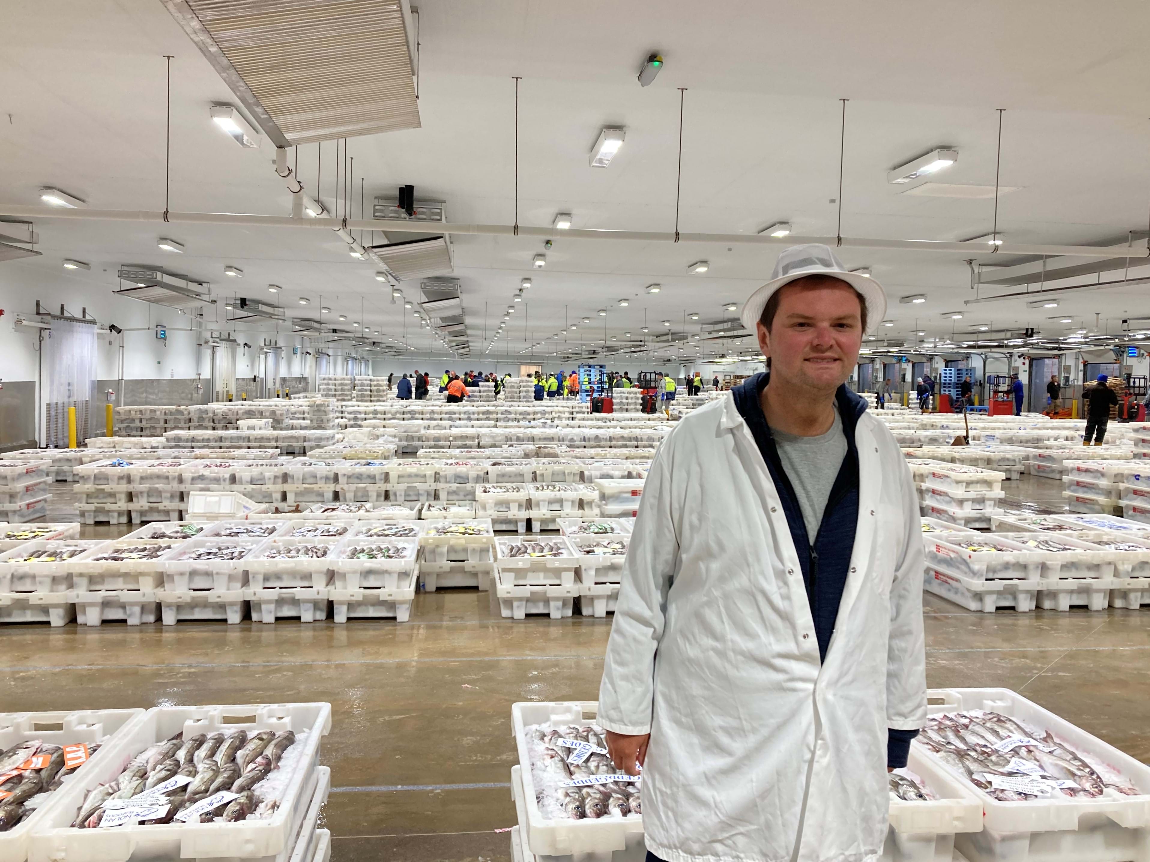 Jack standing in the fish market in front of stacked fish boxes