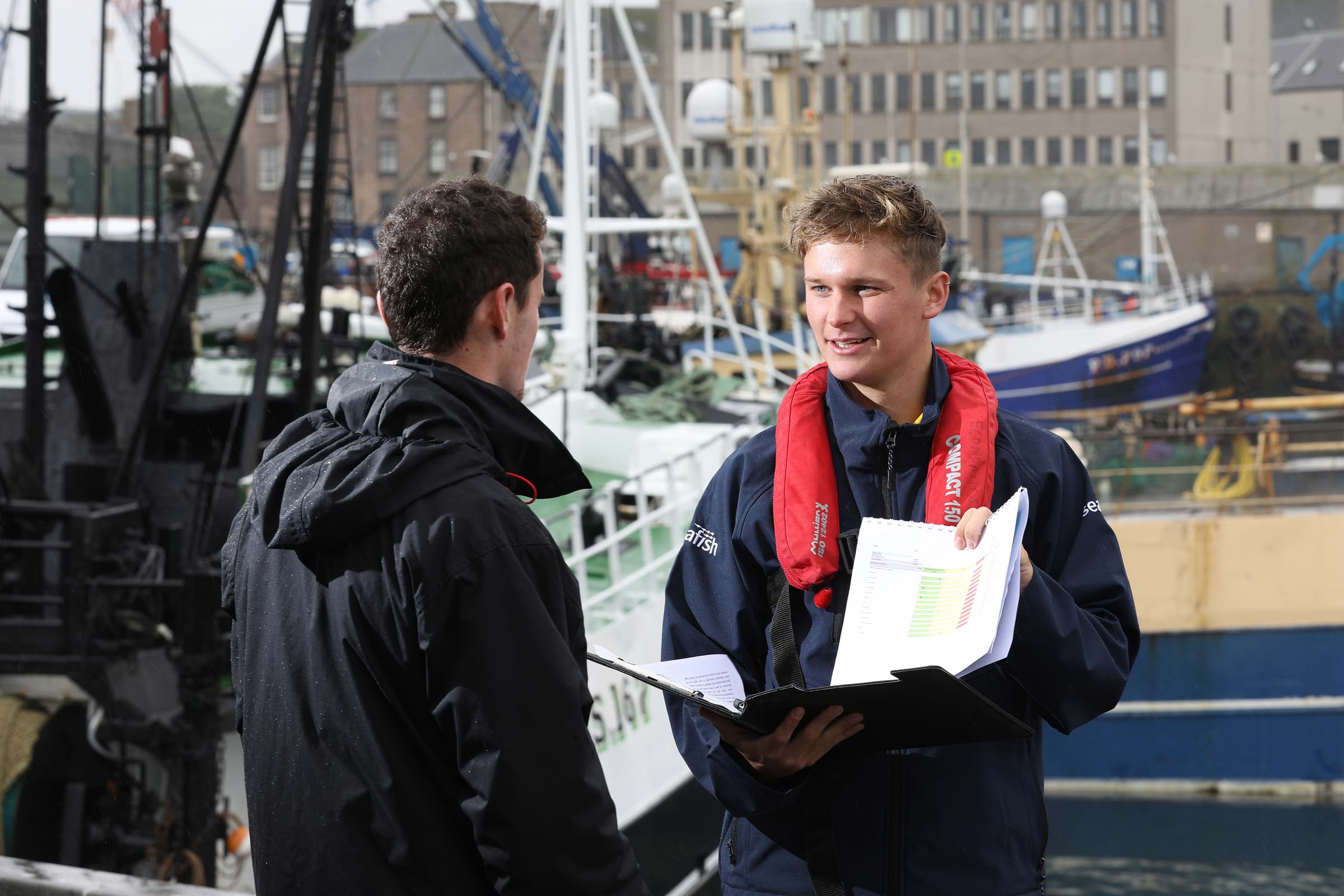 Seafish fleet researcher talking to a fishing vessel owner by the quayside
