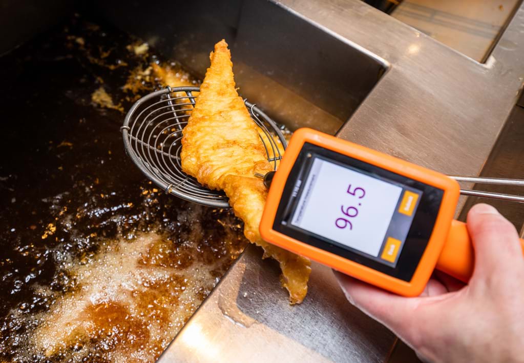 Temperature check of fried fish fillet using a digital thermometer