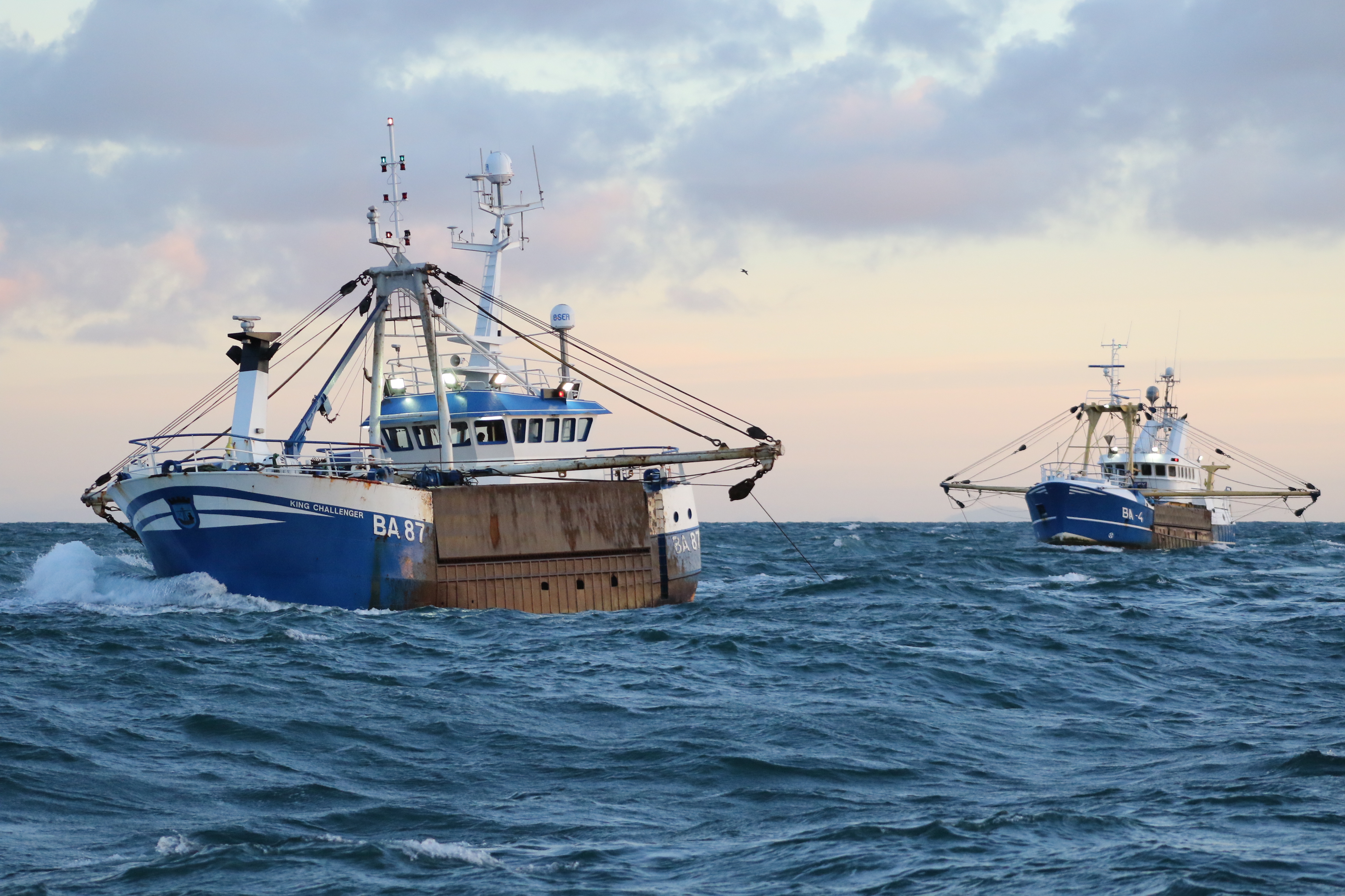 Two trawlers fishing on choppy open waters