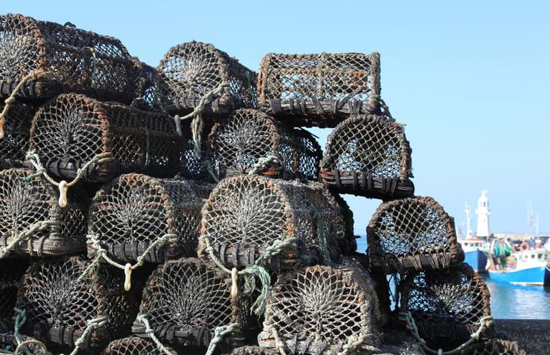 A stack of pots or creels on pier with boat in background