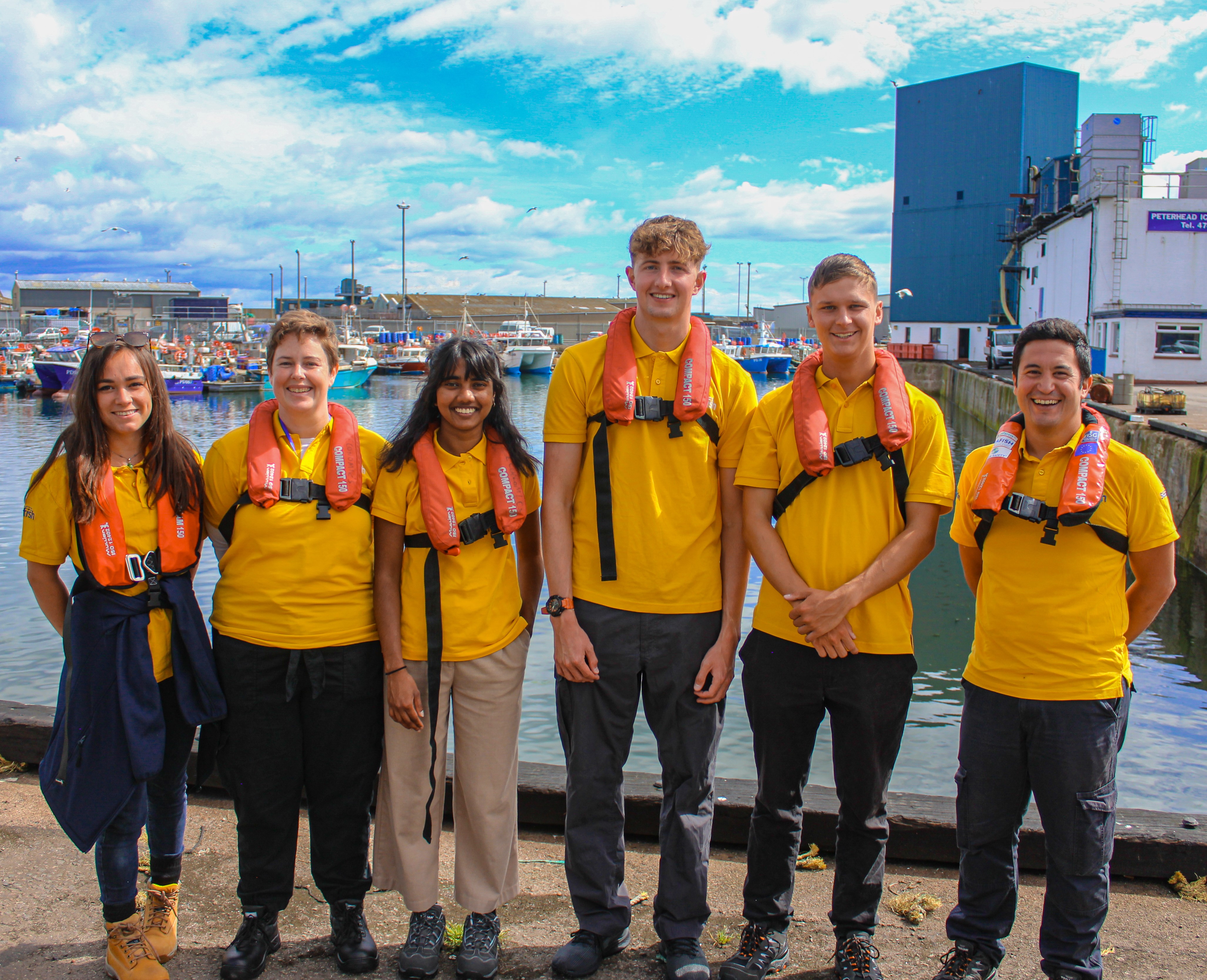 Group of people standing beside each other at a harbour
