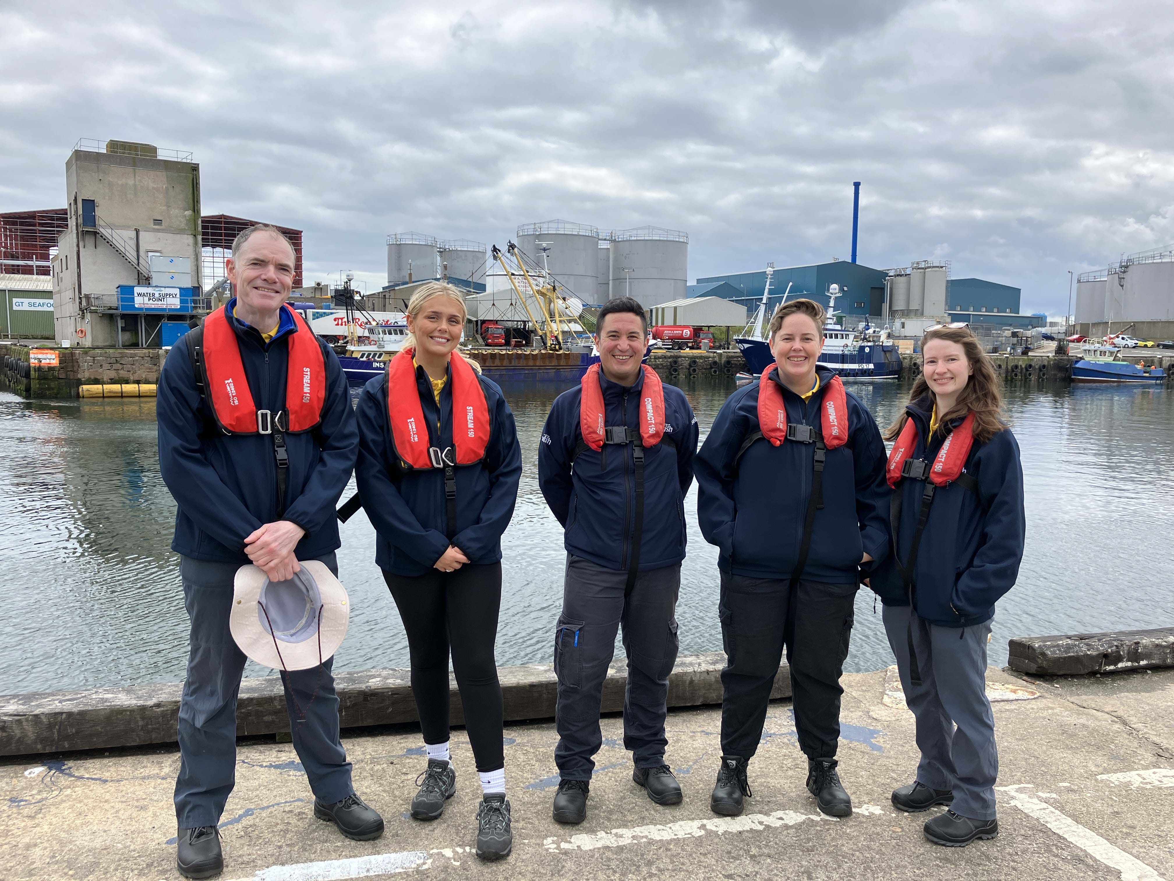 Our fleet survey team stand dockside at a harbour.