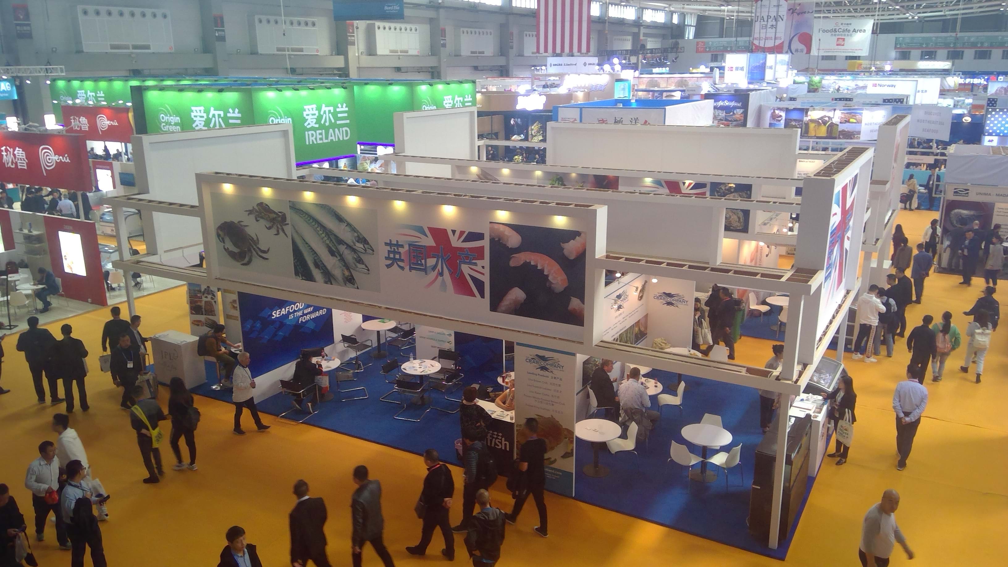 Photo shows a pavilion of exhibitors in a huge conference centre hall. There is a Union Jack flag and images of fish on the display.